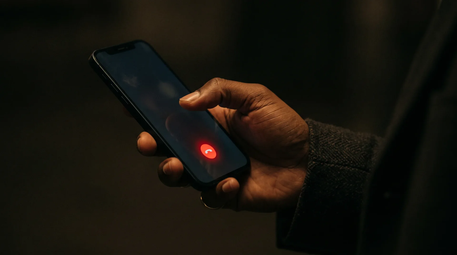 Hand hält ein Smartphone, auf dem Display leuchtet der rote Anruf-Button.